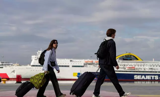 Passengers walk through the port of Piraeus during a 24-hour seafarers' strike over pay, working conditions and safety, alongside protests by port workers against the transport of military equipment through ports, near Athens, Greece, Friday, Oct. 30, 2026. (AP Photo/Thanassis Stavrakis)