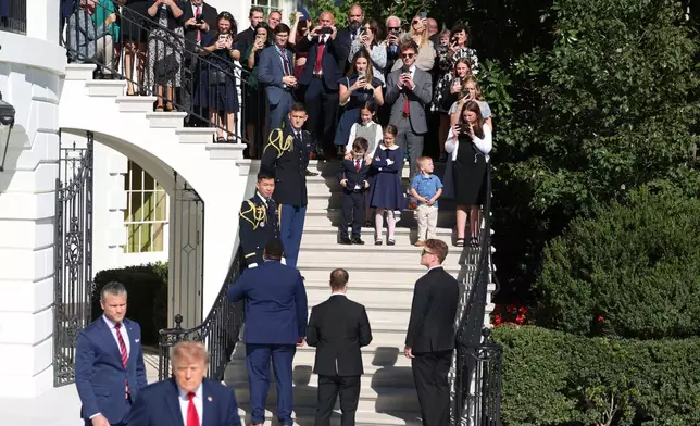 Gold Star families watch as President Donald Trump and Defense Secretary Pete Hegseth walk before departing on Marine One from the South Lawn of the White House, Tuesday, Oct. 6, 2026, in Washington. (AP Photo/Tom Brenner)