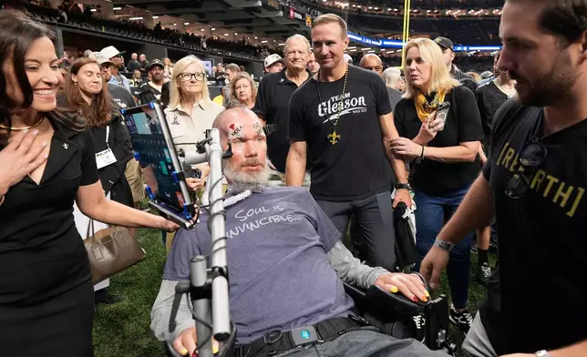 Former New Orleans Saints quarterback Drew Brees, middle right, approaches former player Steve Gleason, middle foreground, before an NFL football game between the Saints and the Atlanta Falcons in New Orleans, Monday, Oct. 5, 2026. (AP Photo/Gerald Herbert)