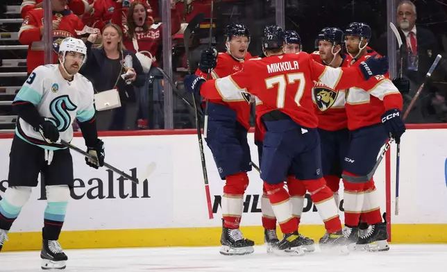 Seattle Kraken center Chandler Stephenson, left, looks on as Florida Panthers center Sam Bennett (9) celebrates with teammates after scoring during the first period of an NHL hockey game, Saturday, Oct. 17, 2026, in Sunrise, Fla. (AP Photo/David Santiago)