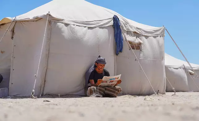 A displaced Yemeni reads a newspaper at the Al-Firdaws camp in Ras Imran on the western outskirts of Aden, Yemen, Monday, Oct. 5, 2026. (AP Photo/Abdulnasser Alseddik)