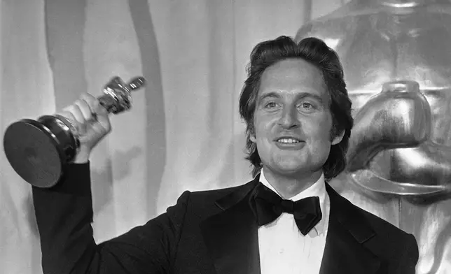 FILE - Michael Douglas, co-producer of the film "One Flew Over the Cuckoo's Nest," holds the Oscar he won by the picture at the Academy Awards in Los Angeles on March 29, 1976. (AP Photo, File)