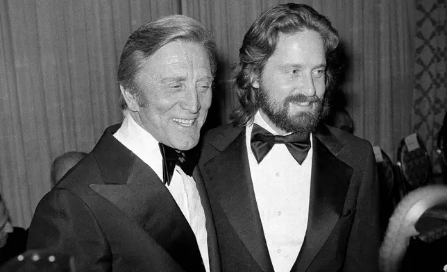 FILE - Kirk Douglas, left, appears with his son Michael Douglas at a Friar's Club dinner in New York, on April 22, 1977. (AP Photo/Carlos Rene Perez, File)