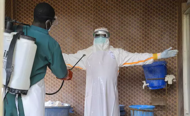A healthcare worker in protective clothing is disinfected by a colleague inside a treatment center for Ebola patients in Beni, North Kivu province, eastern Congo, Saturday, Sept. 26, 2026. (AP Photo/Sebastien Kitsa Musayi)