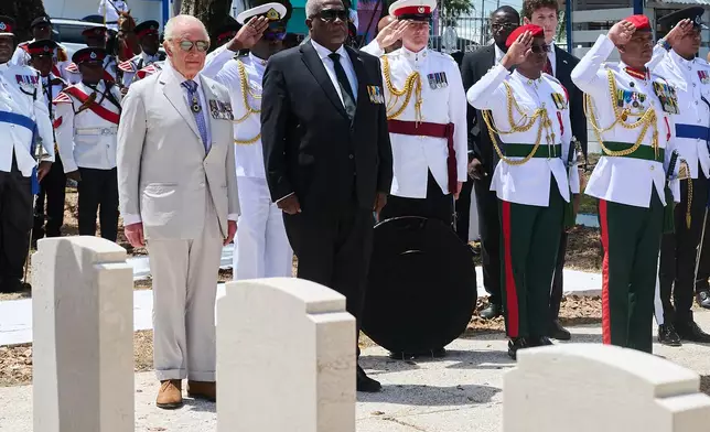 Britain's King Charles III, left, and Guyana's Prime Minister Mark Anthony Phillip, center, attend a wreath-laying ceremony at the Commonwealth War Graves in Georgetown, Guyana, Friday, Oct. 30, 2026. (AP Photo/Delano Williams)