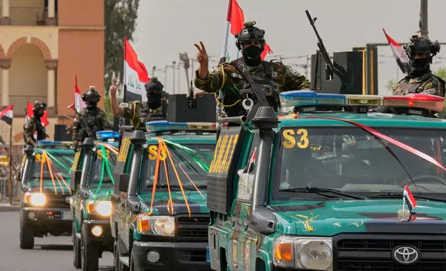 Iraqi security officers flash victory signs as they ride on vehicles decorated with national flags and ribbons during a convoy celebrating the complete withdrawal of U.S. troops from Iraq, in Baghdad, Iraq, Wednesday, Sept. 30, 2026. (AP Photo/Hadi Mizban)