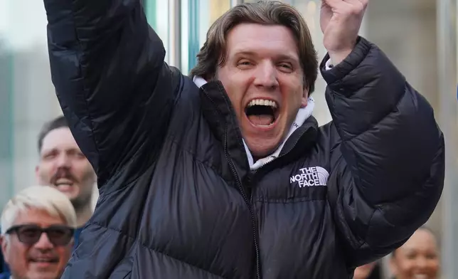 Mike Cronin, the first customer to buy the newly-launched iPhone Duo, reacts outside the Apple store on Fifth Avenue in New York, Friday, Oct. 23, 2026. (AP Photo/Ryan Murphy)