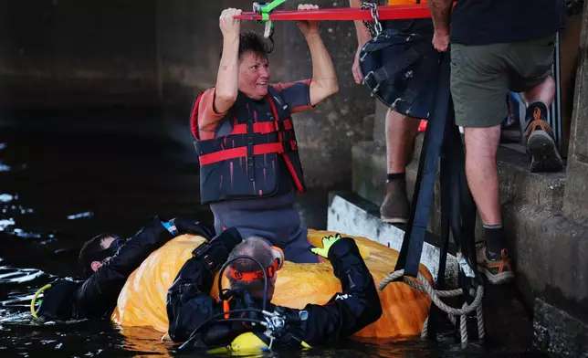 Laura Fairchild is lowered into her giant pumpkin boat before racing in the pumpkin regatta during the annual Harvest Festival, Sunday, Oct. 11, 2026, in Stillwater, Minn. (AP Photo/Ellen Schmidt)