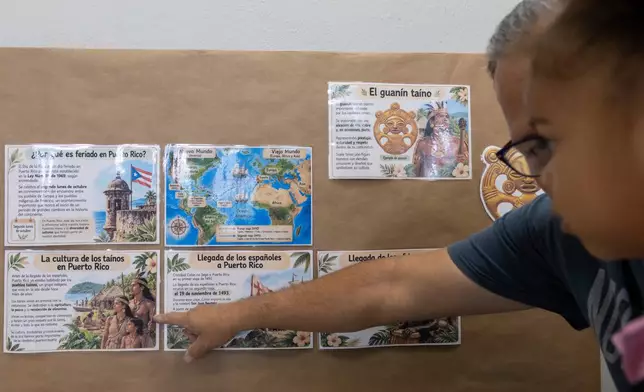 A teacher points to an educational poster in Spanish about Puerto Rican history and the island’s Indigenous Taíno culture, displayed on a classroom wall at the John Cardinal O’Connor Center for Parent and Child Development, a Head Start center operated by The New York Foundling, in San Juan, Puerto Rico, Tuesday, Oct. 13, 2026. (AP Photo/Alejandro Granadillo)