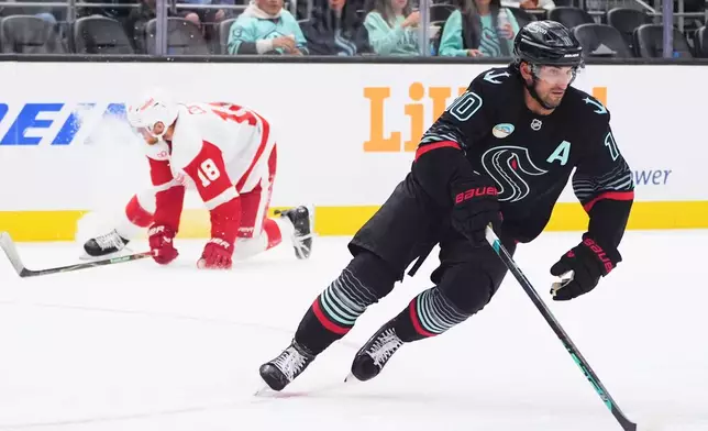 Seattle Kraken center Matty Beniers (10) skates away with the puck as Detroit Red Wings center Andrew Copp (18) gets up after falling to the ice during the second period of an NHL hockey game Tuesday, Oct. 20, 2026, in Seattle. (AP Photo/Lindsey Wasson)