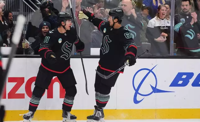 Seattle Kraken right wing Mackie Samoskevich (11) celebrates his goal with defenseman Brandon Montour, right, against the Detroit Red Wings during the first period of an NHL hockey game Tuesday, Oct. 20, 2026, in Seattle. (AP Photo/Lindsey Wasson)