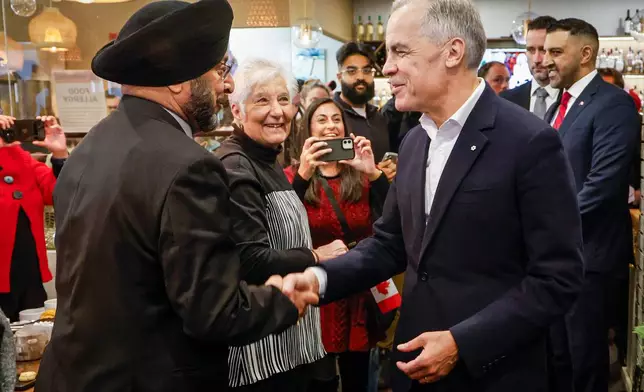 Canada Prime Minister Mark Carney, center right, meets with supporters at a restaurant in Calgary, Canada, Thursday, Oct. 15, 2026. (Jeff McIntosh/The Canadian Press via AP)