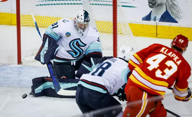 Seattle Kraken goalie Philipp Grubauer, left, deflects a shot from Calgary Flames' Adam Klapka during second period of an NHL hockey game in Calgary, Alberta, Friday, Oct. 30, 2026. (Jeff McIntosh/The Canadian Press via AP)