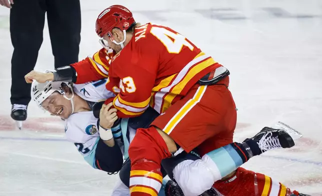 Seattle Kraken's Curtis Douglas, left, fights with Calgary Flames' Adam Klapka during the first period of an NHL hockey game in Calgary, Alberta, Friday, Oct. 30, 2026. (Jeff McIntosh/The Canadian Press via AP)