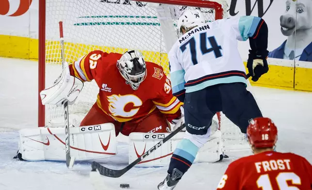 Seattle Kraken's Bobby McMann, right, tries to get the puck past Calgary Flames goalie Dustin Wolf during the first period of an NHL hockey game in Calgary, Alberta, Friday, Oct. 30, 2026. (Jeff McIntosh/The Canadian Press via AP)
