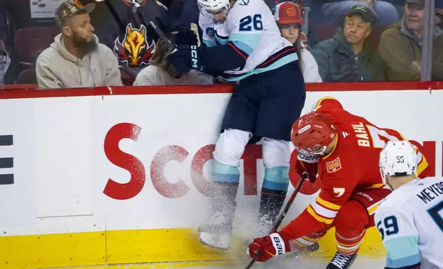 Seattle Kraken's Ryan Winterton, left, checks Calgary Flames' Kevin Bahl, upper right, during the first period of an NHL hockey game in Calgary, Alberta, Friday, Oct. 30, 2026. (Jeff McIntosh/The Canadian Press via AP)