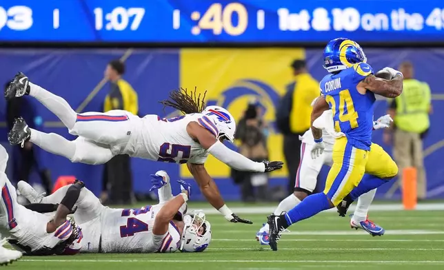 Los Angeles Rams running back Blake Corum, right, runs the ball as Buffalo Bills defensive end Michael Hoecht, upper left, and safety Cole Bishop try to tackle him during the second half of an NFL football game, Monday, Oct. 12, 2026, in Inglewood, Calif. (AP Photo/Scott Strazzante)