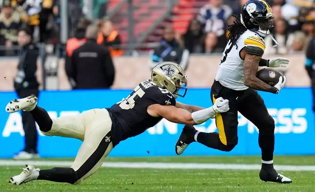 Pittsburgh Steelers running back Rico Dowdle (13) gets away from New Orleans Saints linebacker Kaden Elliss (55) during an NFL football game in Saint-Denis, outside Paris, Sunday, Oct. 25, 2026. (AP Photo/Steve Luciano)