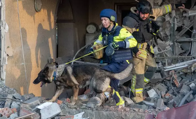 Rescuers with a search dog look for victims among the rubble of a house after a Russian air attack in Kharkiv, Ukraine, Tuesday, Oct. 20, 2026. (AP Photo/Andrii Marienko)