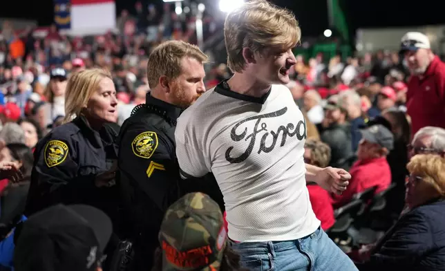 Police remove a protester as President Donald Trump speaks at a campaign rally at Pitt–Greenville Airport, Tuesday, Oct. 20, 2026, in Greenville, N.C. (AP Photo/Alex Brandon)