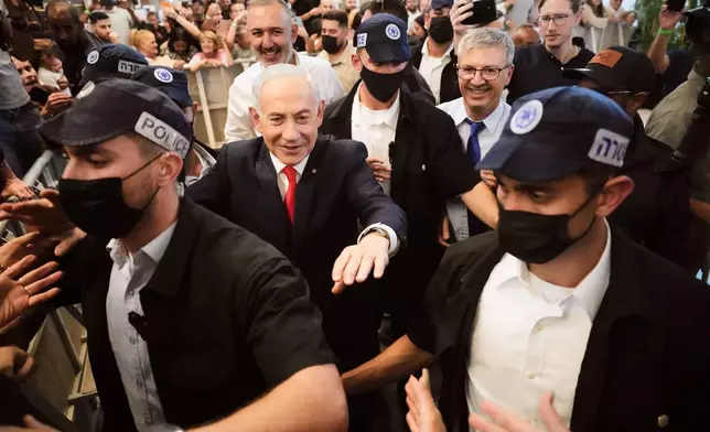 Israeli Prime Minister Benjamin Netanyahu, leader of the Likud party, gestures to supporters as security personnel surround him while he campaigns ahead of the country's general election at a shopping mall in Ramla, Israel, Monday, Oct. 19, 2026. (AP Photo/Ariel Schalit)