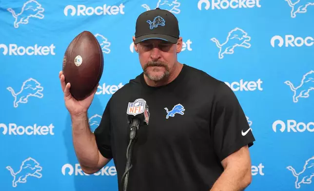 Detroit Lions head coach Dan Campbell dedicates a game ball to radio play-by play broadcaster Dan Miller, ollowing the death of his wife recently, after an NFL football game against the Arizona Cardinals in Glendale, Ariz., Sunday, Oct. 11, 2026. (AP Photo/Ross D. Franklin)