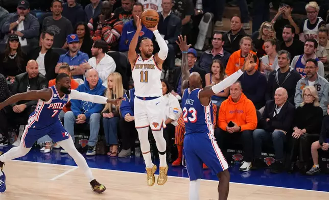 New York Knicks guard Jalen Brunson (11) shoots as Philadelphia 76ers forward LeBron James (23) and Jaylen Brown (7) defend during the first half of an NBA basketball game Tuesday, Oct. 20, 2026, in New York. (AP Photo/Frank Franklin II)