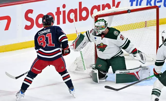 Winnipeg Jets' Kyle Connor (81) has a shot go over Minnesota Wild goaltender Calvin Pickard (31) and the net during first period NHL hockey action in Winnipeg, Manitoba, Tuesday, Oct. 13, 2026. (Fred Greenslade/The Canadian Press via AP)