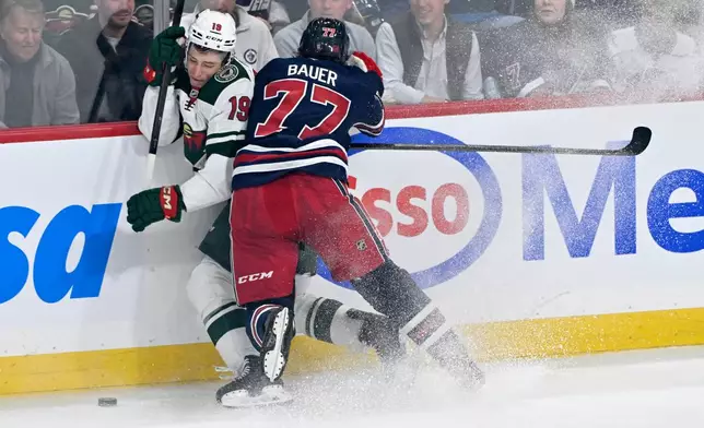 Winnipeg Jets' Tyrel Bauer (77) checks Minnesota Wild's Tyler Pitlick (19) during first period NHL hockey action in Winnipeg, Manitoba, Tuesday, Oct. 13, 2026. (Fred Greenslade/The Canadian Press via AP)