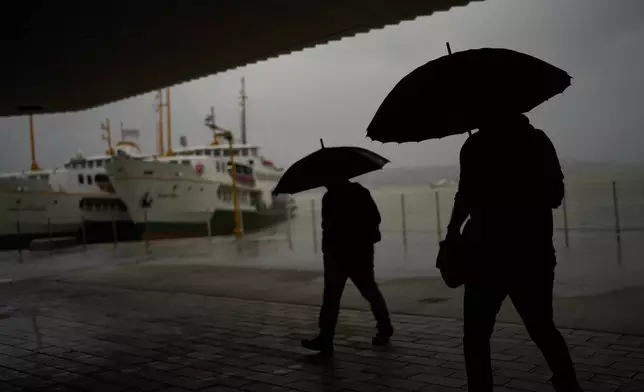 Commuters arrive to the Kabatas ferry terminal during a rain in Istanbul, Turkey, Thursday, Oct. 15, 2026. (AP Photo/Francisco Seco)