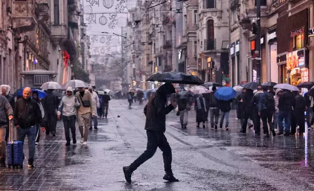 Pedestrians walk along Istiklal main street under a heavy rain in Istanbul, Turkey, Wednesday, Oct. 14, 2026. (Huseyin Ozdemir/DIA Photo via AP)