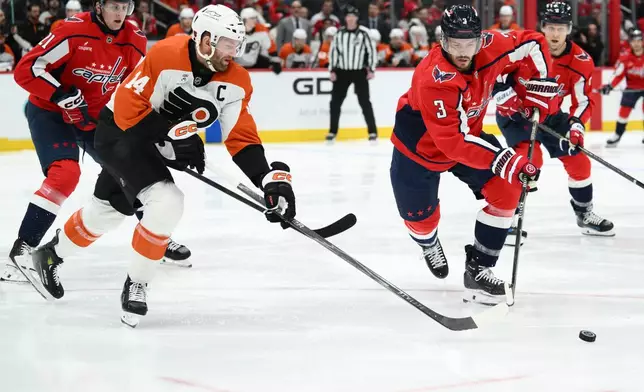 Washington Capitals defenseman Matt Roy (3) and Philadelphia Flyers center Sean Couturier (14) chase the puck during the first period of an NHL hockey game, Wednesday, Oct. 28, 2026, in Washington. (AP Photo/Nick Wass)