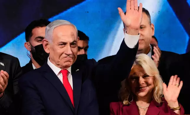 Israeli Prime Minister Benjamin Netanyahu, accompanied by his wife, Sara, waves to supporters at Likud party headquarters in Jerusalem after the release of the first exit poll results in Israel's general election, Wednesday, Oct. 28, 2026. (AP Photo/Ohad Zwigenberg)