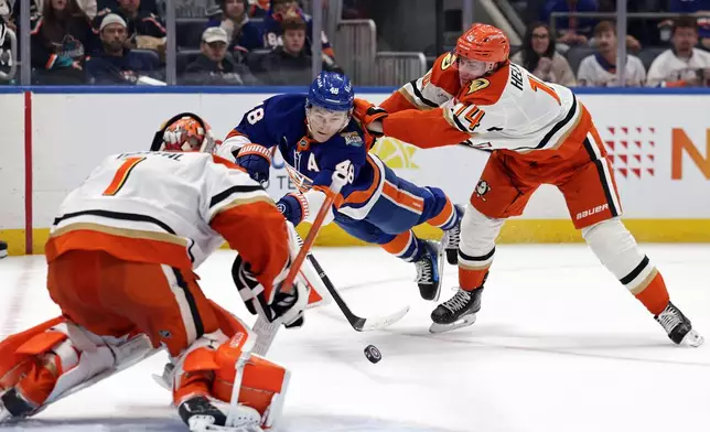 New York Islanders defenseman Matthew Schaefer (48) shoots towards Anaheim Ducks goaltender Lukas Dostal as he is pushed by Ducks defenseman Drew Helleson (14) during the second period of an NHL hockey game Tuesday, Oct. 20, 2026, in Elmont, N.Y. (AP Photo/Adam Hunger)