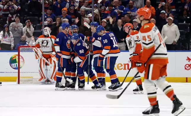 New York Islanders right wing Simon Holmstrom (92) is congratulated by teammates after scoring a goal past Anaheim Ducks goaltender Lukas Dostal during the first period of an NHL hockey game Tuesday, Oct. 20, 2026, in Elmont, N.Y. (AP Photo/Adam Hunger)