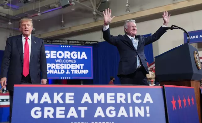 President Donald Trump listens as Georgia U.S. Senate candidate Rep. Mike Collins, R-Ga., speaks at a campaign rally at Guardian Centers of Georgia, Saturday, Oct. 24, 2026, in Perry, Ga. (AP Photo/Mark Schiefelbein)