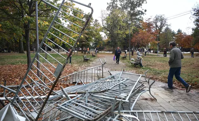 People walk in a park used as a camp by supporters of the right-wing Serbian Progressive Party (SNS) where tents and vehicles were set on fire by celebrating crowds after Aleksandar Vucic, the party leader conceded defeat in the parliamentary election, held on Sunday, in Belgrade, Serbia, Monday, Oct. 26, 2026. (AP Photo/Armin Durgut)