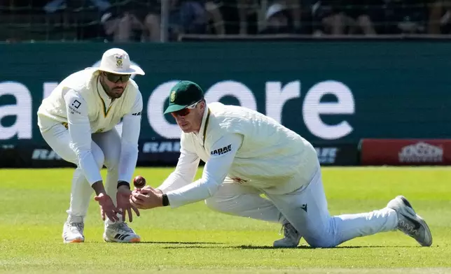 South Africa's Simon Harmer, right, attempts to field the ball as South Africa's Aiden Markram covers him on day five of the second cricket test match between South Africa and Australia, in Gqeberha, South Africa, Thursday, Oct. 22, 2026. (AP Photo/Themba Hadebe)