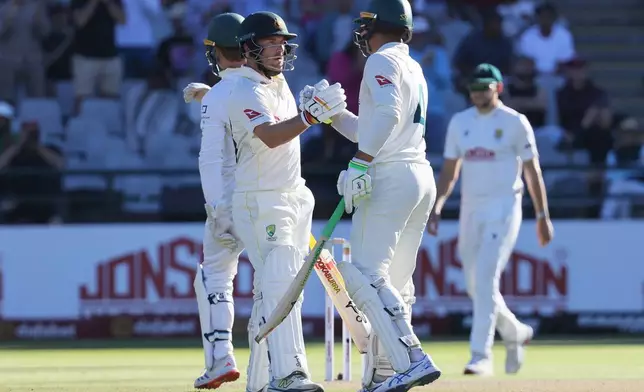 Australia's Josh Inglis, left, congratulated by Australia's Alex Carey after his fifty on day two of the third cricket test match between South Africa and Australia, in Cape Town, South Africa, Wednesday, Oct. 28, 2026. (AP Photo/Halden Krog)