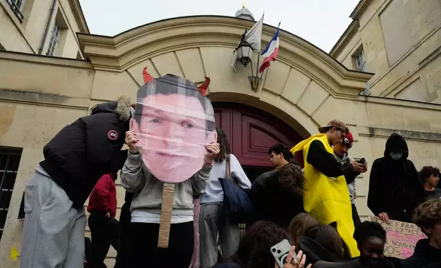 Students hold a banner with the face of French Education and Research Minister Edouard Geffray as they stand in front of a blockaded high school to protest against under-resourced schools, in Paris, Friday, Oct. 9, 2026. (AP Photo/Teresa Suarez)