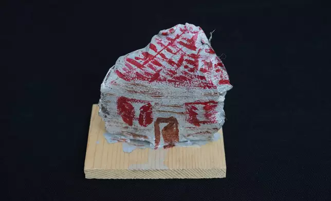 An artwork depicting a Lebanese traditional house, created by visual artist Lina Jouni from shrapnel collected from Israeli military munitions, is displayed at her home in the village of Roumin, southern Lebanon, Sunday, Oct. 25, 2026. (AP Photo/Hassan Ammar)