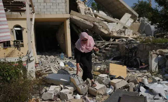 Visual artist Lina Jouni walks through the rubble of a house destroyed by an Israeli strike as she searches for shrapnel from Israeli military munitions to use in her artworks in the village of Roumin, southern Lebanon, Sunday, Oct. 25, 2026. (AP Photo/Hassan Ammar)