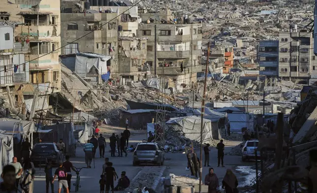 Palestinians walk along a street surrounded by buildings destroyed in Israeli military strikes during the Israel-Hamas war in Gaza City, Tuesday, Oct. 6, 2026. (AP Photo/Jehad Alshrafi)