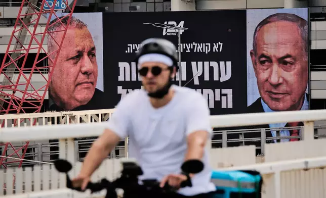 A man rides bicycle past a television channel advertisement featuring Israeli Prime Minister Benjamin Netanyahu, right, and his main rival, opposition candidate Gadi Eisenkot, ahead of Israel's general election, in Ramat Gan, Israel, Wednesday, Sept. 23, 2026. (AP Photo/Oded Balilty)