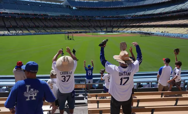 Los Angeles Dodgers fans raise their hands for a ball as the heat soars during batting practice before Game 1 of a National League Division Series baseball game Saturday, Oct. 3, 2026, in Los Angeles. (AP Photo/Jae C. Hong)