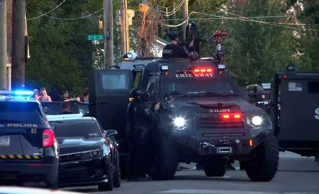 In this image from video provided by WJET, police gather outside the scene of a shooting in Erie, Pa., on Friday evening, Oct. 9, 2026. (Matt Barnum/WJET via AP)