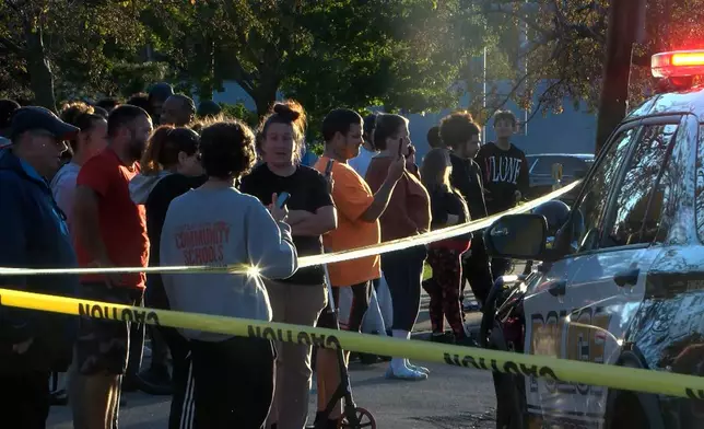 In this image from video provided by WJET, bystanders gather outside the scene of a shooting in Erie, Pa., on Friday evening, Oct. 9, 2026. (Matt Barnum/WJET via AP)