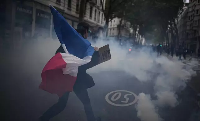 A protester holds a French flag during a demonstration against rising living costs in Lyon, France, Saturday, Oct. 24, 2026. (AP Photo/Laurent Cipriani)