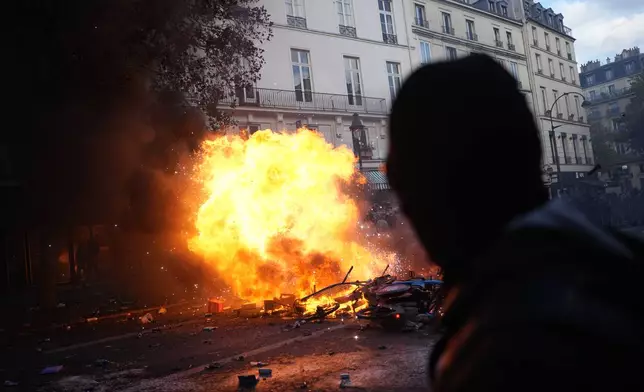 Protesters stand in front of burning bicycles during a demonstration against rising living costs, joining students' grievances, in Paris, Saturday, Oct. 17, 2026. (AP Photo/Thibault Camus)