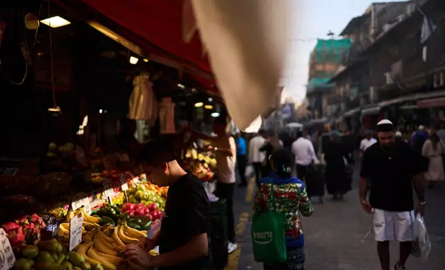 A worker arranges a display of fruits at the Mahane Yehuda market, Wednesday, Oct. 21, 2026, in Jerusalem. (AP Photo/David Goldman)